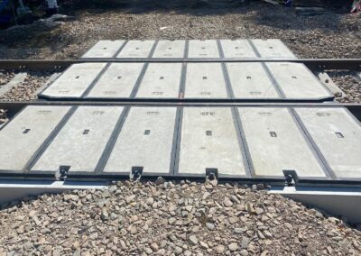Concrete precast panels laid over gravel ballast to form a temporary/under-construction railroad bed between rails on a construction site