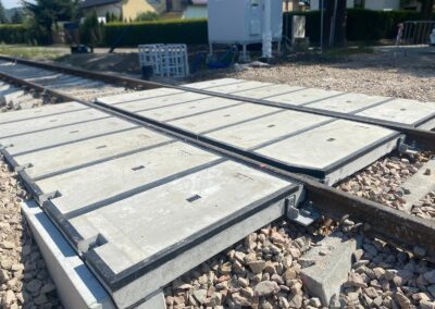 Concrete railroad crossing panels laid over gravel with rails passing through, under construction in a suburban area